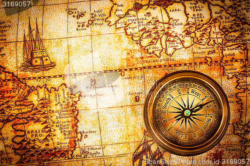 Image of Vintage compass lies on an ancient world map.