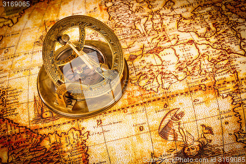 Image of Vintage compass lies on an ancient world map.