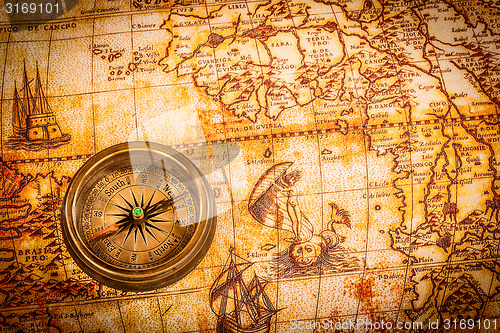 Image of Vintage compass lies on an ancient world map.