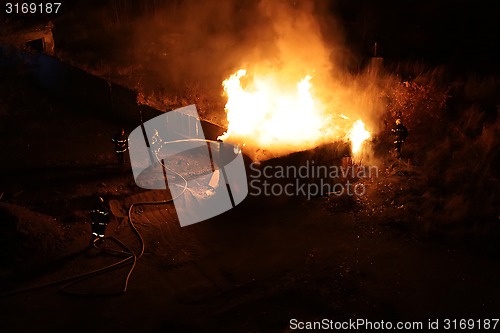 Image of Squad of Four Firefighters Dousing a Burning Shed