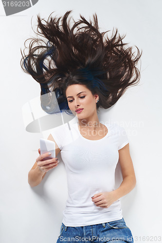 Image of Woman lying on her back and using phone