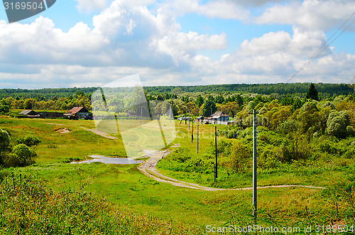 Image of Rural landscape with dirt road, houses and power poles in the sp