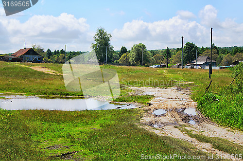 Image of Rural landscape with dirt road, houses and power poles in the sp