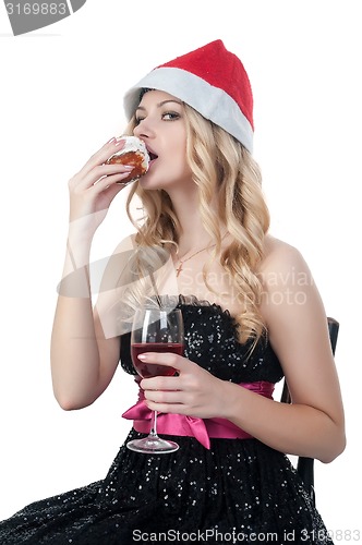 Image of Attractive blond woman in christmas hat eats cake