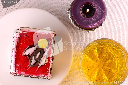 Image of sweet cake on white plate with wine and candle