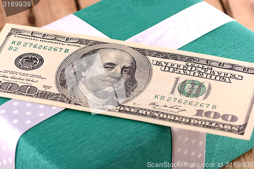 Image of Holiday bonus.  american money on green gift box