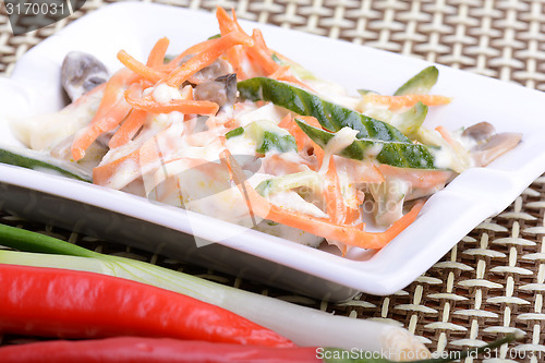 Image of fresh salad on white plate and red pepper