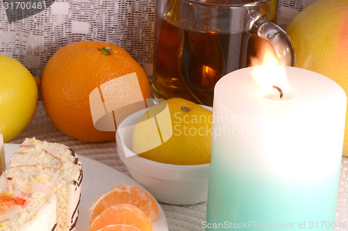 Image of sweet cake on white plate with fruits and candle