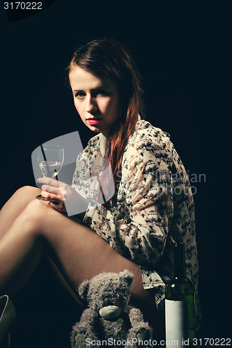 Image of beautiful young brunette woman holding a bottle of white wine