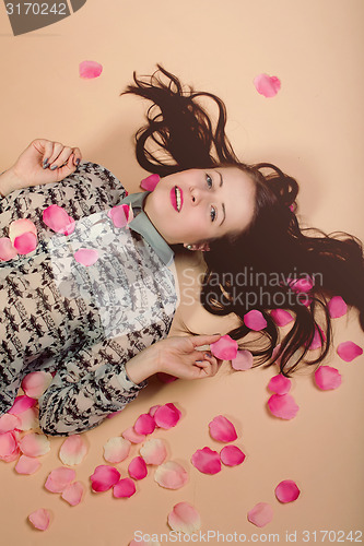 Image of atractive brunette girl lying on beige background