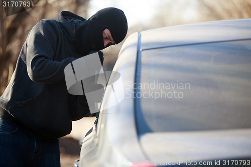 Image of Thief stealing automobile car at daylight street in city