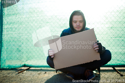 Image of Homeless man holds blank cardboard for your text