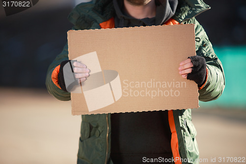 Image of Homeless man holds blank cardboard for your own text