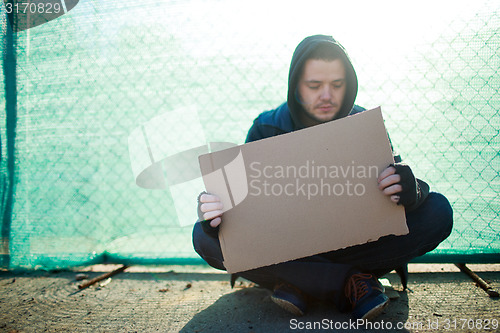 Image of Homeless man holds blank cardboard for your text