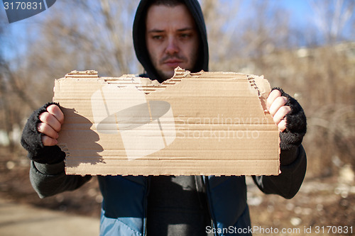 Image of Homeless man holds blank cardboard for your text