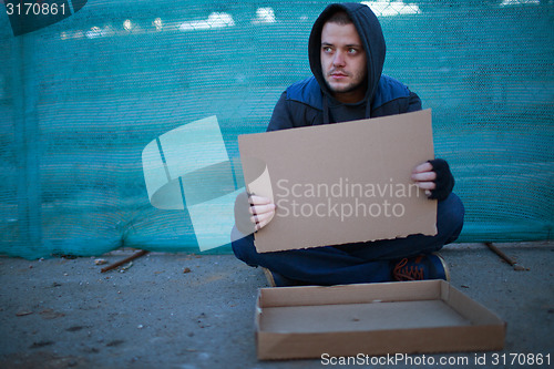 Image of Homeless man holds blank cardboard for your text