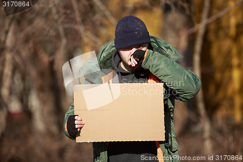 Image of Homeless man holds blank cardboard for your own text