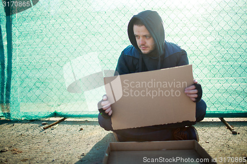 Image of Homeless man holds blank cardboard for your text