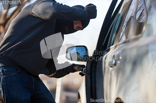 Image of Thief stealing automobile car at daylight street in city