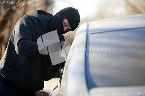 Image of Thief stealing automobile car at daylight street in city