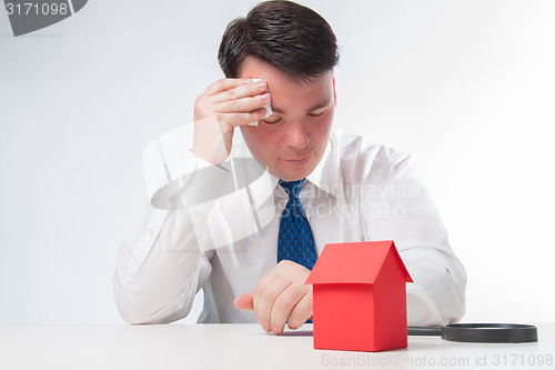 Image of Sad Man with a magnifying glass and paper house