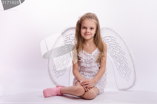 Image of Sitting girl in an angel costume on a white background