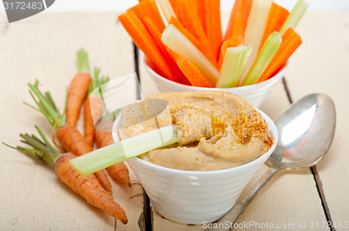 Image of fresh hummus dip with raw carrot and celery 