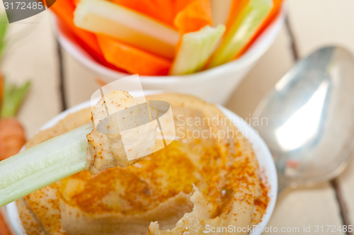 Image of fresh hummus dip with raw carrot and celery 