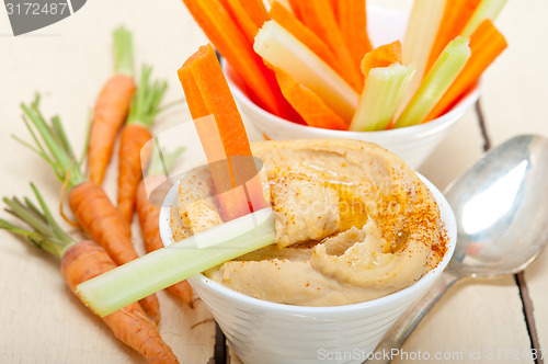 Image of fresh hummus dip with raw carrot and celery 