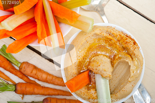 Image of fresh hummus dip with raw carrot and celery 