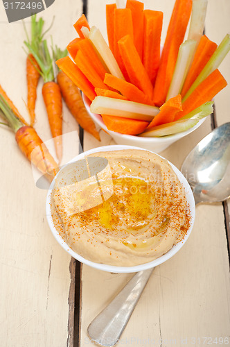 Image of fresh hummus dip with raw carrot and celery 