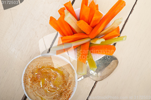 Image of fresh hummus dip with raw carrot and celery 