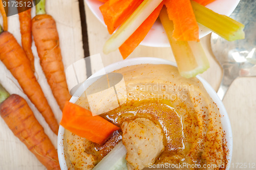 Image of fresh hummus dip with raw carrot and celery 