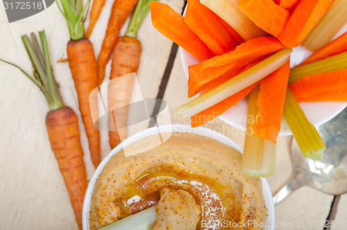 Image of fresh hummus dip with raw carrot and celery 