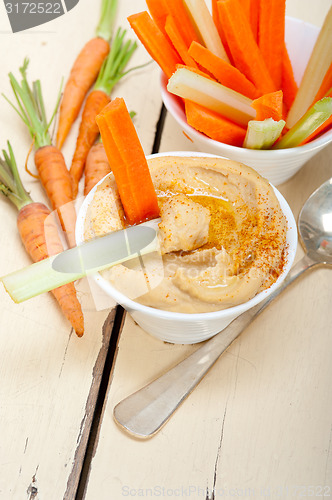 Image of fresh hummus dip with raw carrot and celery 