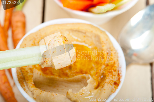 Image of fresh hummus dip with raw carrot and celery 