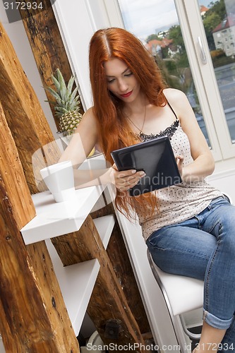 Image of Sitting Woman with a Glass of Drink and a Tablet