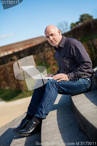 Image of Man sitting on a bench using a laptop