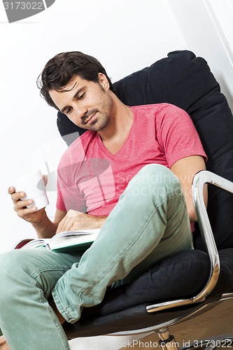 Image of Man Sitting on Chair with Book and a Drink