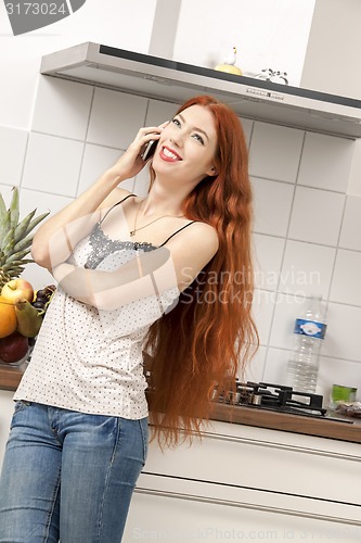 Image of Happy Woman Talking Through Phone at the Kitchen