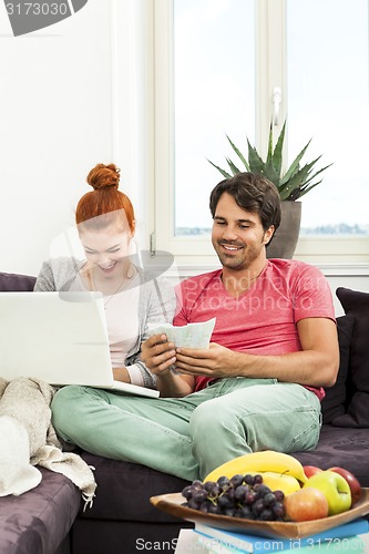 Image of Couple at the Couch with Laptop, Card and Money