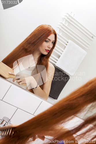 Image of Woman Brushing her Hair In Front a Mirror