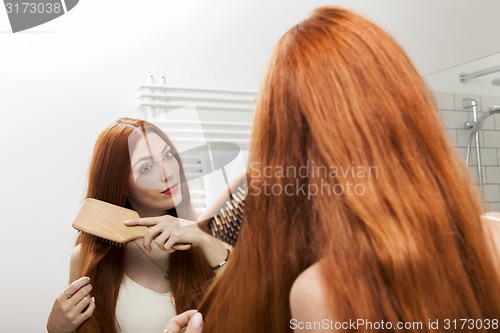 Image of Woman Brushing her Hair In Front a Mirror