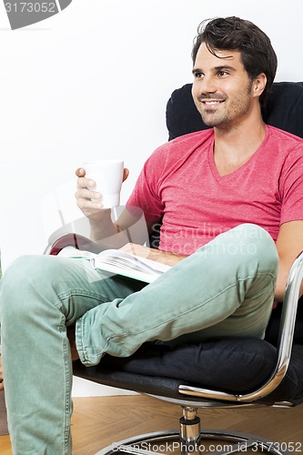 Image of Man Sitting on Chair with Book and a Drink