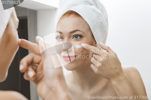 Image of Woman After Shower Applying Cream on her Face