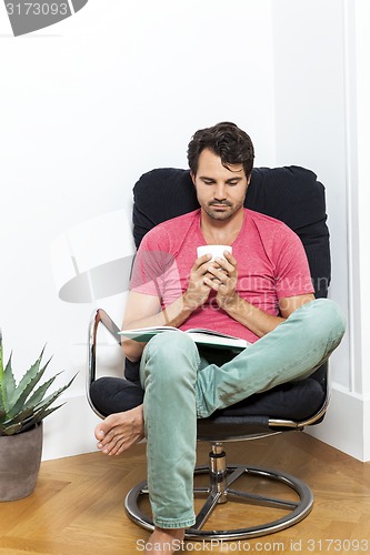 Image of Man Sitting on Chair with Book and a Drink