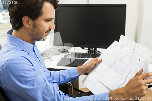 Image of Young man reading written agreements for work