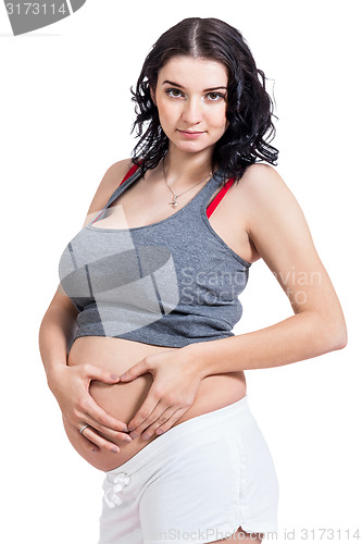 Image of Young pregnant woman making a heart gesture