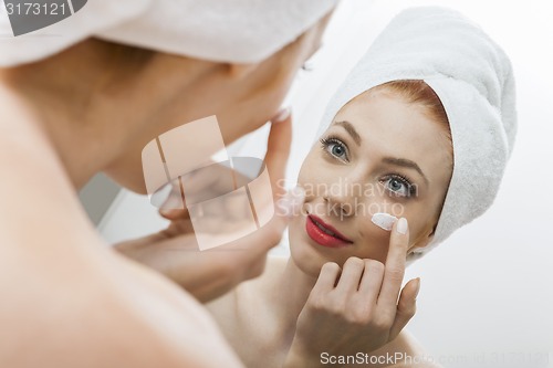 Image of Woman After Shower Applying Cream on her Face