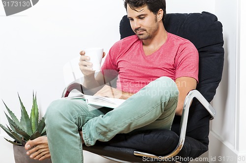 Image of Man Sitting on Chair with Book and a Drink